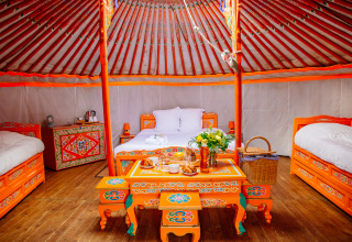 Intérieur d'une yourte colorée au Yurt at Domaine EcÔtelia en France, avec meubles peints et ambiance chaleureuse.