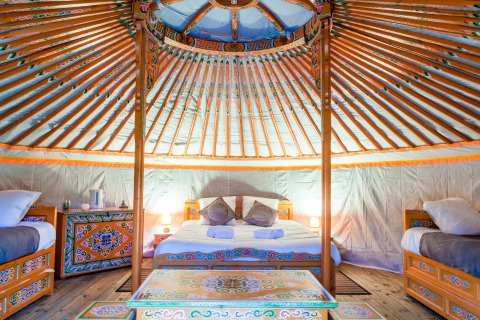 Innenansicht einer traditionellen Jurte mit bunten Möbeln im Domaine EcÔtelia, Frankreich.