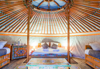Innenansicht einer traditionellen Jurte mit bunten Möbeln im Domaine EcÔtelia, Frankreich.