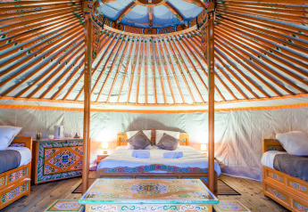 Innenansicht einer traditionellen Jurte mit bunten Möbeln im Domaine EcÔtelia, Frankreich.