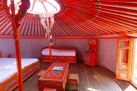 Intérieur d’une yourte mongole traditionnelle au Domaine EcÔtelia en France avec décor coloré et lits.