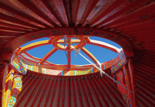Vista de la abertura decorada del techo de una yurta en Domaine EcÔtelia, Francia, bajo el cielo azul.