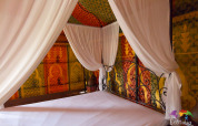 Intérieur de la tente safari Caïdale au Domaine EcÔtelia, France, avec des murs en tissus colorés et motifs.