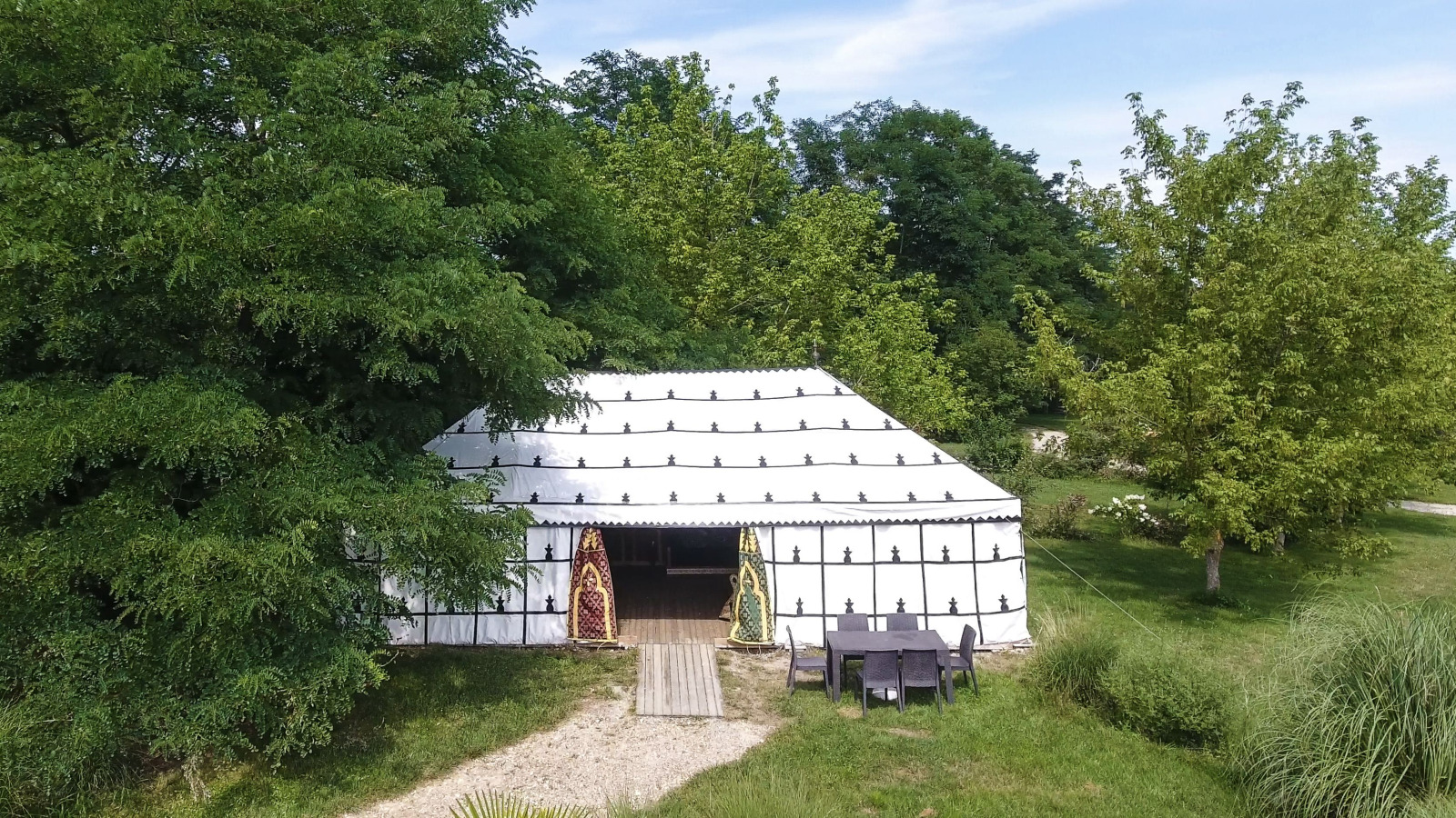 Safari-tent «Caïdale» bij Domaine EcÔtelia in Frankrijk, omgeven door weelderige bomen en natuur.