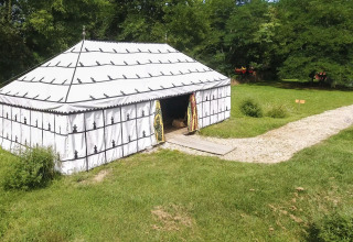 La tenda safari 'Caïdale' al Domaine EcÔtelia in Francia, circondata da prato, alberi e un sentiero di pietra.