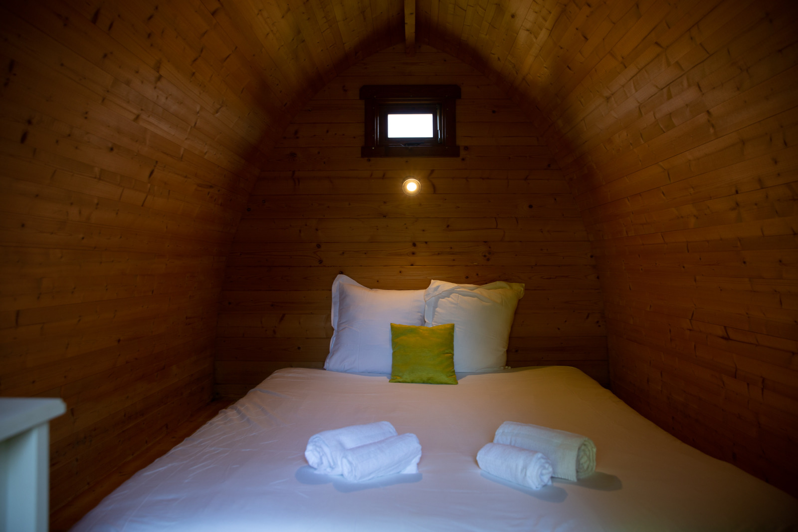Gezellige houten pod met bed en handdoeken bij Domaine EcÔtelia in Frankrijk, sfeervol ingericht.