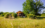 Safari-Zelt im Domaine EcÔtelia in Frankreich, umgeben von Wiesen und Bäumen an einem sonnigen Tag.