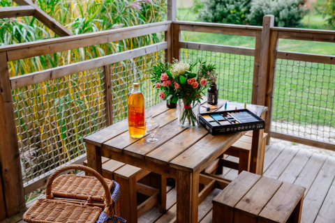 Mesa de madera con flores, vino, cesta de picnic y set de pintura en Tent Safari, Domaine EcÔtelia en Francia.