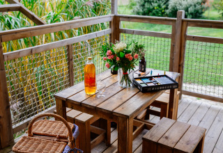 Mesa de madera con flores, vino, cesta de picnic y set de pintura en Tent Safari, Domaine EcÔtelia en Francia.