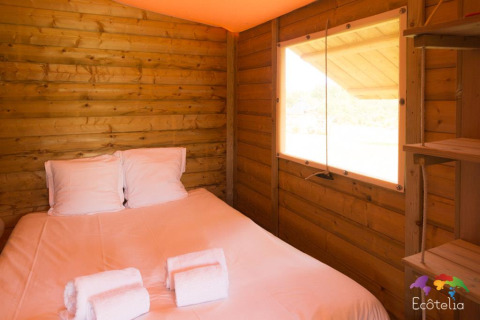Innenansicht eines Safari-Zeltes im Domaine EcÔtelia in Frankreich mit Doppelbett und Holzverkleidung.