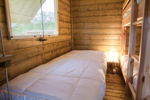 Innenaufnahme eines gemütlichen Holzraums mit Etagenbetten im Zelt 'Safari' auf Domaine EcÔtelia in Frankreich.