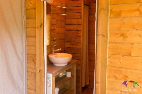 Interno bagno in legno della tenda 'Safari' al Domaine EcÔtelia in Francia, dotato di lavabo moderno.