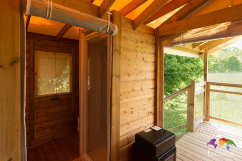 Vista dalla terrazza della tenda Safari al Domaine EcÔtelia in Francia, con pareti in legno e natura verde.