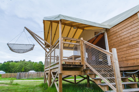 Tenda safari con terrazza rialzata e amaca in legno al Domaine EcÔtelia, Francia, immersa nella natura.