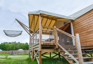 Tienda safari con terraza elevada de madera y hamaca en Domaine EcÔtelia, Francia, rodeada de naturaleza.