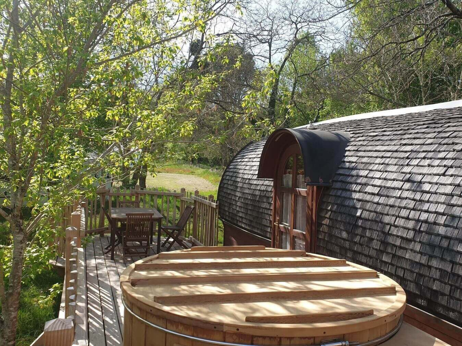 Gezellig houten terras met buitenbad bij de Caravan-hut in Domaine EcÔtelia, Frankrijk.