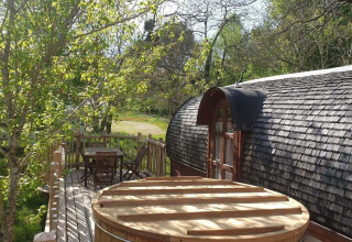 Knus houten terras met buitenbad aan de Caravan-hut bij Domaine EcÔtelia in Frankrijk.