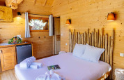Gemütliches Schlafzimmer mit Holzverkleidung und rustikalem Bett im indonesischen Haus bei Domaine EcÔtelia, Frankreich.