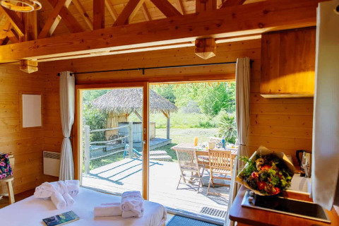 Vue intérieure d'une cabane indonésienne au Domaine EcÔtelia en France, ouverte sur une terrasse en bois.
