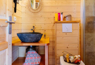 Badezimmer im indonesischen Haus bei Domaine EcÔtelia, Frankreich, mit Holzverkleidung und Steinwaschbecken.