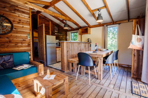 Innenansicht der Océania Lodge bei Domaine EcÔtelia in Frankreich mit Holzdekor und gemütlichem Essbereich.