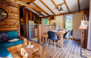 Vista interior de Océania Lodge en Domaine EcÔtelia, Francia, con decoración de madera y área de comedor acogedora.