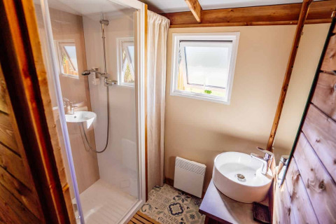 Modernes Badezimmer mit Holzdekor, Dusche, Waschbecken und Fenster im Océania Lodge bei Domaine EcÔtelia, Frankreich.