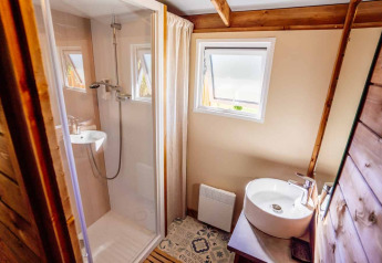 Cozy bathroom with shower, round sink, window and wooden accents at Océania Lodge, Domaine EcÔtelia, France.