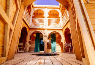 Innenansicht der Riad-Lodge aus Holz mit Rundbögen und offenem Dach im Domaine EcÔtelia, Frankreich.