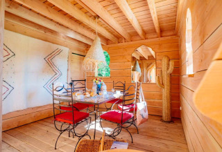 Helles Holzinterieur in einer Lodge des Domaine EcÔtelia in Frankreich mit Esstisch und roten Stühlen.