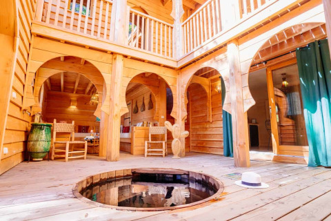 Innenhof der Lodge „Riad“ im Domaine EcÔtelia, Frankreich, mit Holzinterieur, runden Bögen und kleinem Whirlpool.