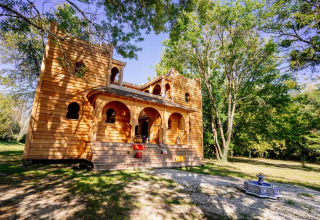 Holzlodge namens «Riad» bei Domaine EcÔtelia in Frankreich, umgeben von Bäumen unter blauem Himmel.