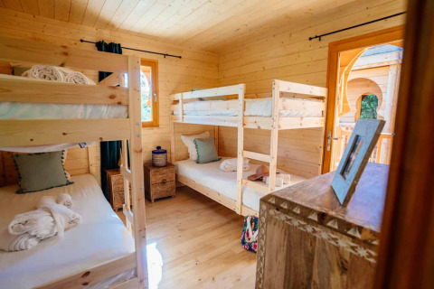 Innenaufnahme eines gemütlichen Holzraums mit zwei Etagenbetten in der Lodge 'Riad' bei Domaine EcÔtelia, Frankreich.