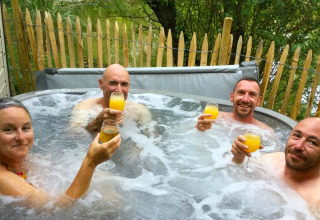 Quattro adulti si godono delle bevande nella vasca idromassaggio al Zen Mobile Home, Ushuaïa Villages Le Parc de la Grève, Francia.