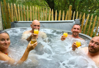 Vier volwassenen genieten van drankjes in het bubbelbad bij Zen Mobile Home, Ushuaïa Villages Le Parc de la Grève, Frankrijk.