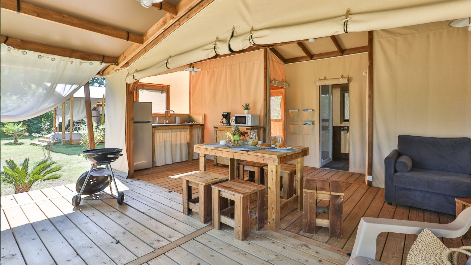 Binnenaanzicht van een Cotton Ecolodge safaritent met keuken, eettafel en zithoek in Frankrijk.