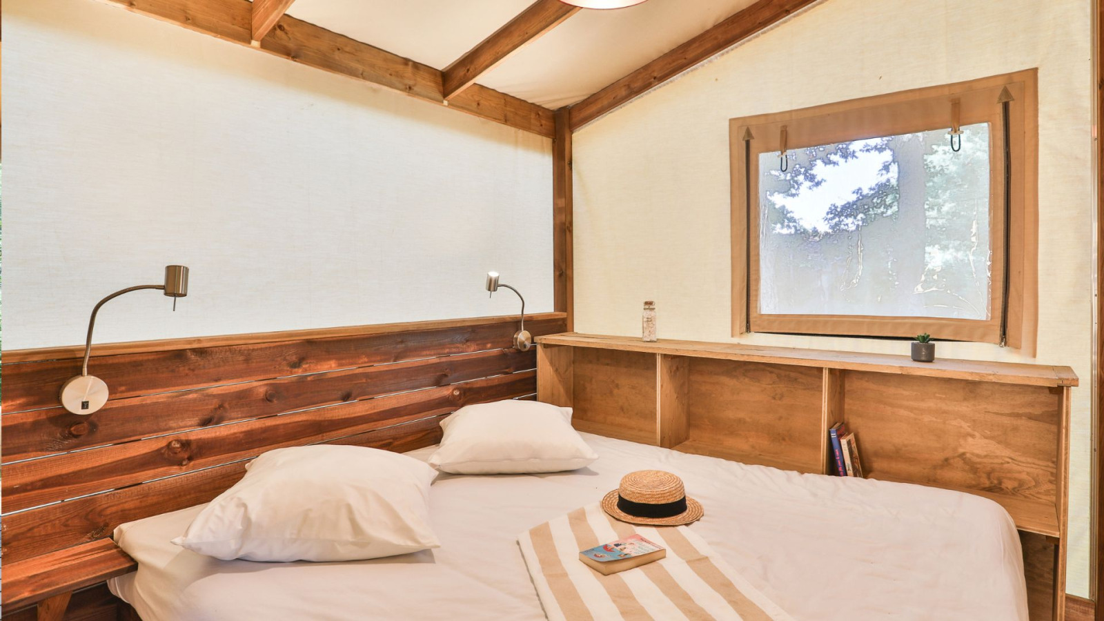 Slaapkamer in een Cotton Ecolodge safaritent bij Ushuaïa Villages Le Parc de la Grève in Frankrijk met houten interieur.