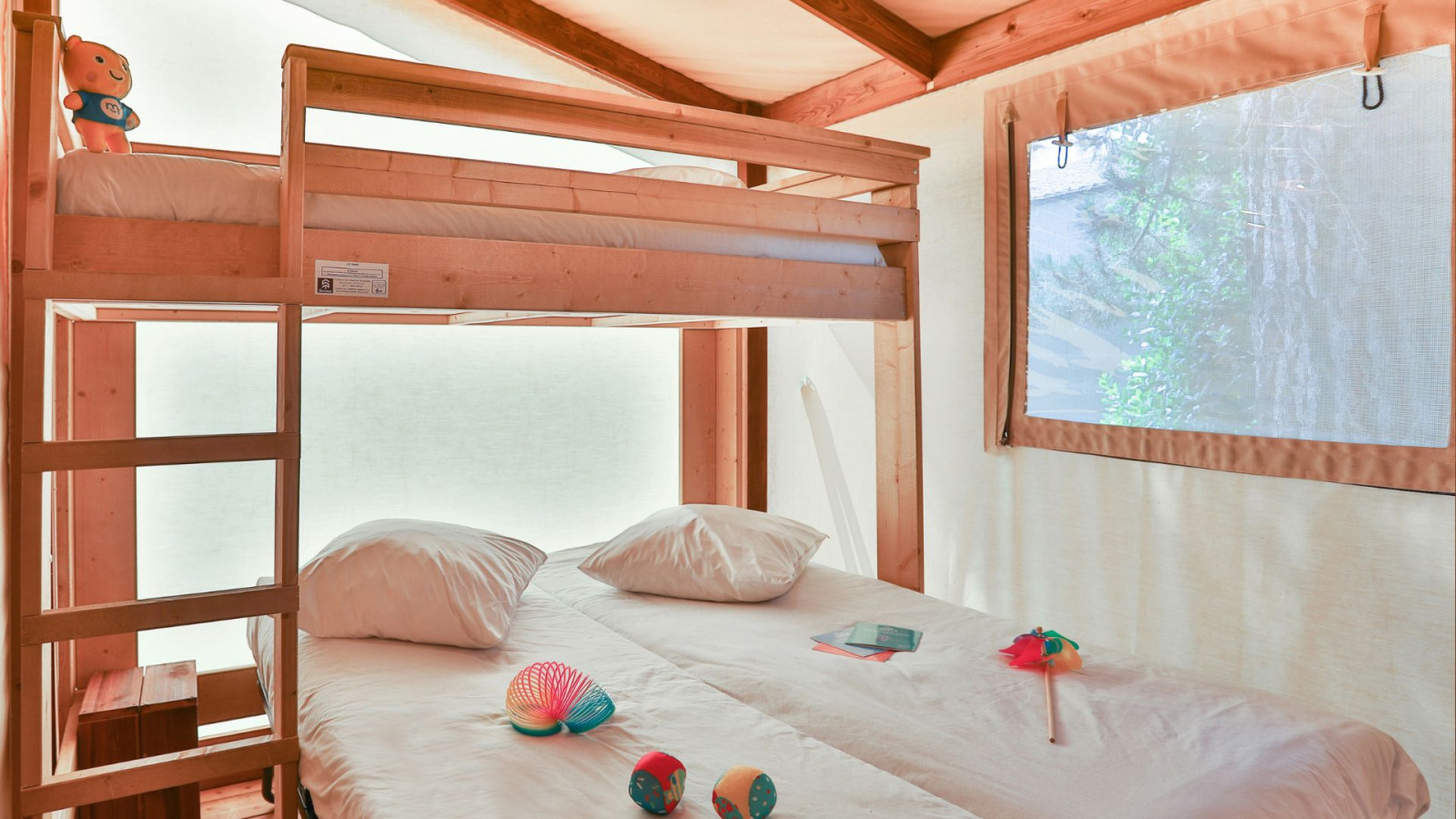 Interieur van een Cotton Ecolodge safaritent met stapelbed en tweepersoonsbed bij Ushuaïa Villages Le Parc de la Grève.