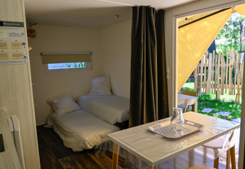Interior view of Cocosweet Ecolodge at Ushuaïa Villages Le Parc de la Grève, France, showing beds and table.