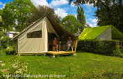 Deux personnes assises devant une tente Ecolodge au Ushuaïa Villages Le Parc de la Grève, France, entourées de verdure.