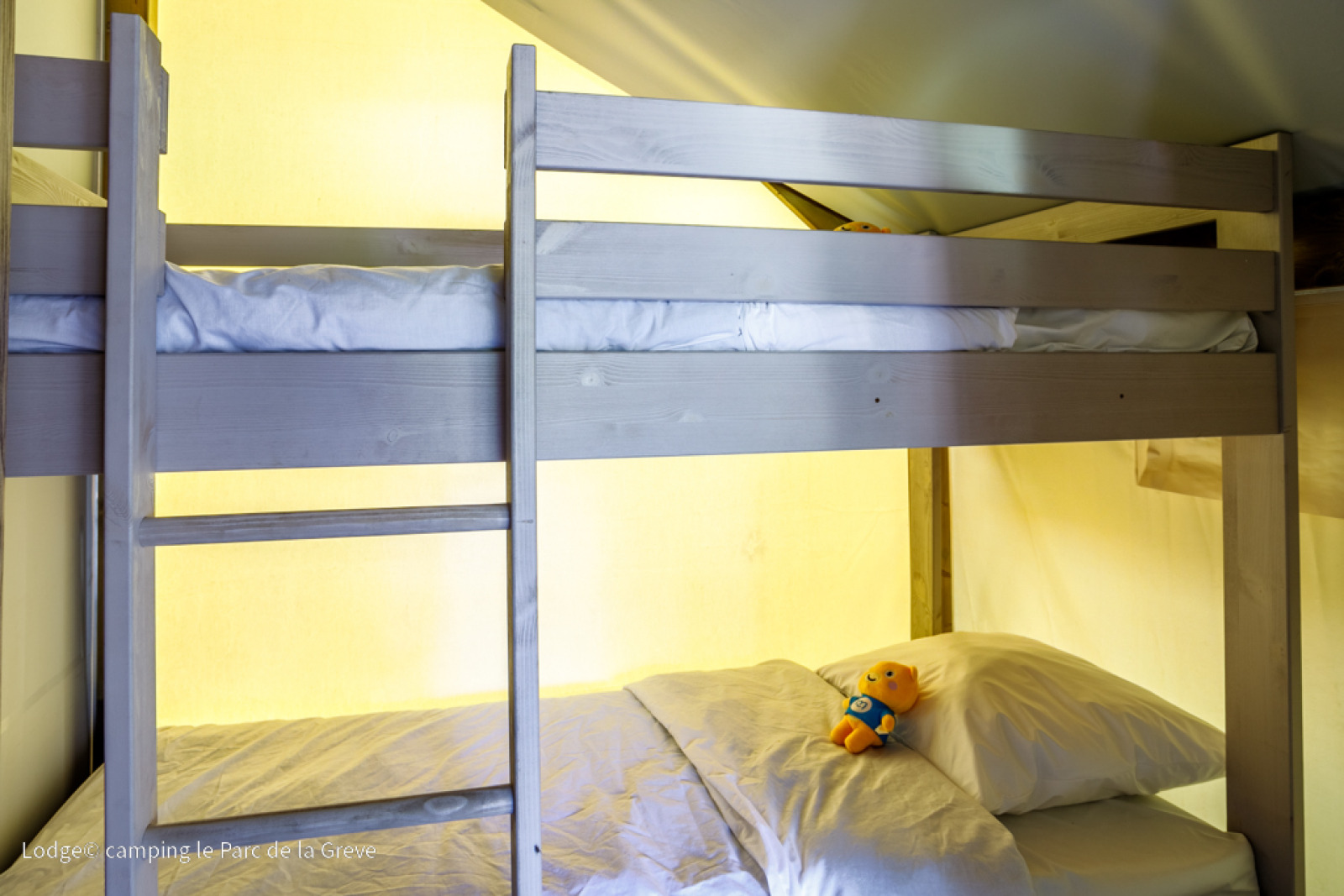 Stapelbedden met beddengoed en knuffel in een Ecolodge Tent bij Ushuaïa Villages Le Parc de la Grève, Frankrijk.