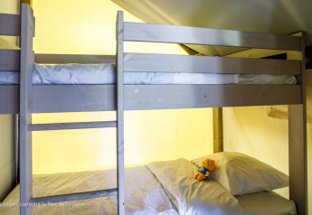 Lits superposés avec literie et peluche dans une tente Ecolodge chez Ushuaïa Villages Le Parc de la Grève, France.
