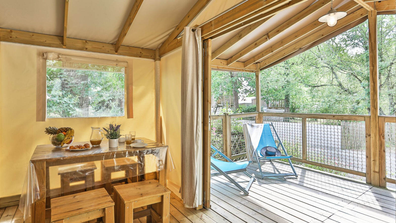Safaritent 'Sahari Ecotent Mindervaliden' bij Ushuaïa Villages Le Parc de la Grève in Frankrijk met houten veranda.