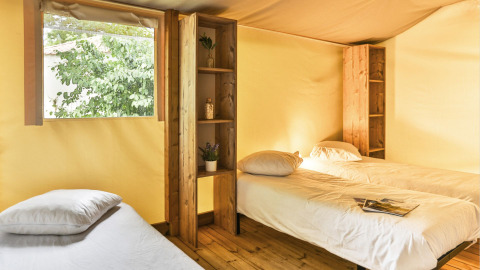 Interieur van de Sahari Ecotent Mindervaliden met drie eenpersoonsbedden en houten planken in Ushuaïa Villages Le Parc de la Grève.