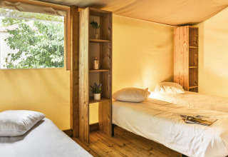 Interieur van de Sahari Ecotent Mindervaliden met drie eenpersoonsbedden en houten planken in Ushuaïa Villages Le Parc de la Grève.