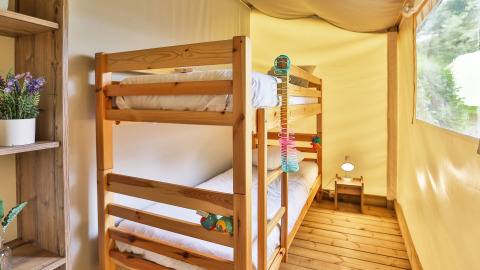 Lichte kamer in een safaritent met houten stapelbed, houten vloer en raam in Ushuaïa Villages Le Parc de la Grève.