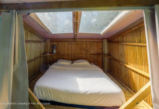 Vista interior de una tienda Campétoile con cama doble y tragaluz en Ushuaïa Villages Le Parc de la Grève, Francia.