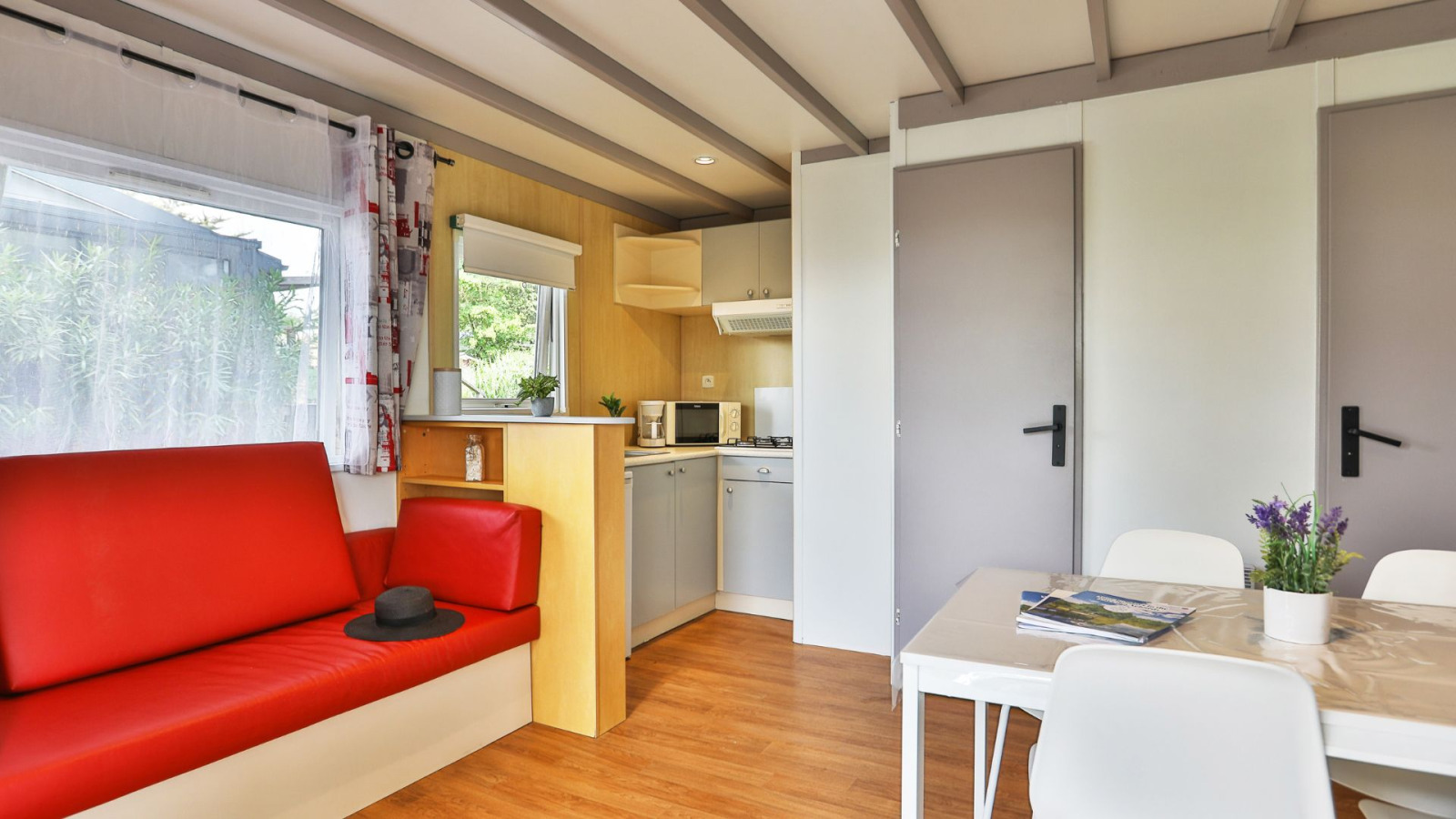 Binnenkant van Relax Chalet met rode bank, kitchenette en eettafel in Ushuaïa Villages Le Parc de la Grève, Frankrijk.