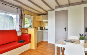 Interno di Relax Chalet con divano rosso, angolo cottura e tavolo da pranzo a Ushuaïa Villages Le Parc de la Grève, Francia.