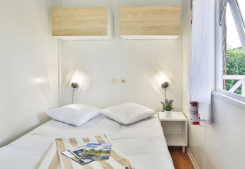 Dormitorio luminoso con cama doble, mesita y ventana abierta en Relax Chalet de Ushuaïa Villages, Francia.